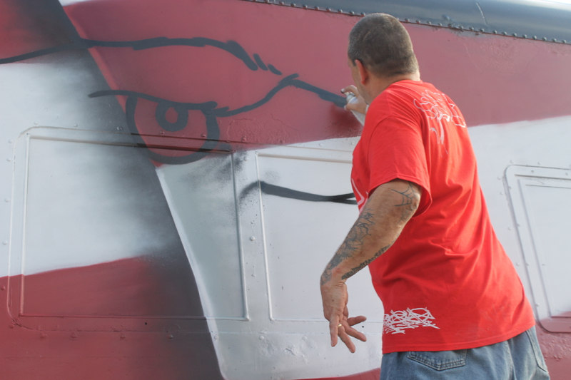 Duster, UA at work sketching out the mural on a railroad car this afternoon at the Railroad Museum of L.I. in Riverhead.Photo: Denise Civiletti