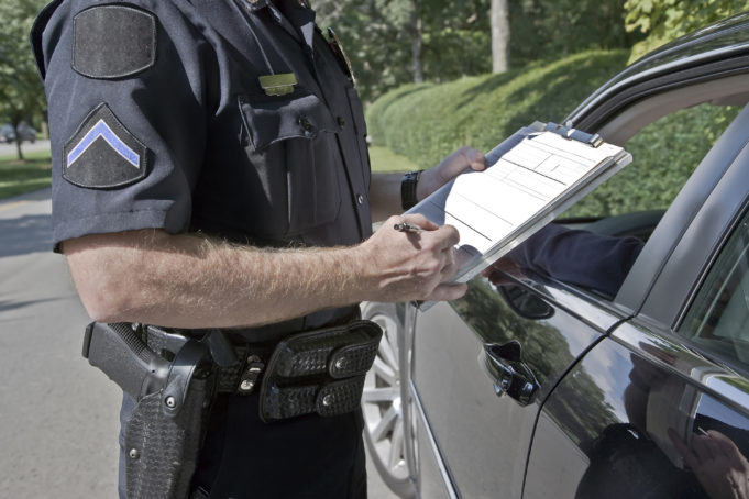 A police officer gives a speeding ticket to a driver.