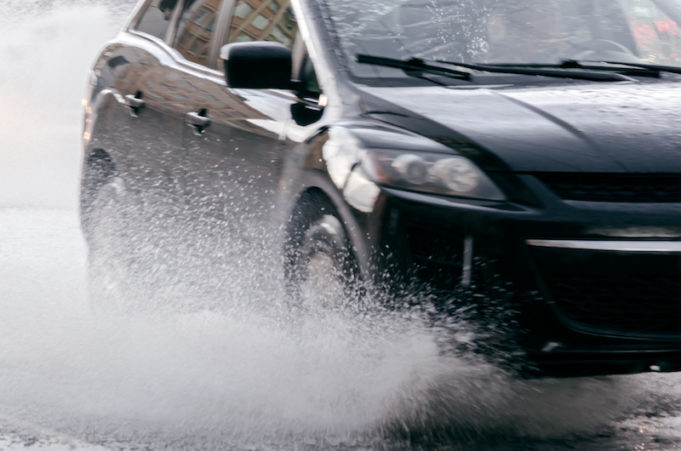 rain water splashing from car wheels on flooded road