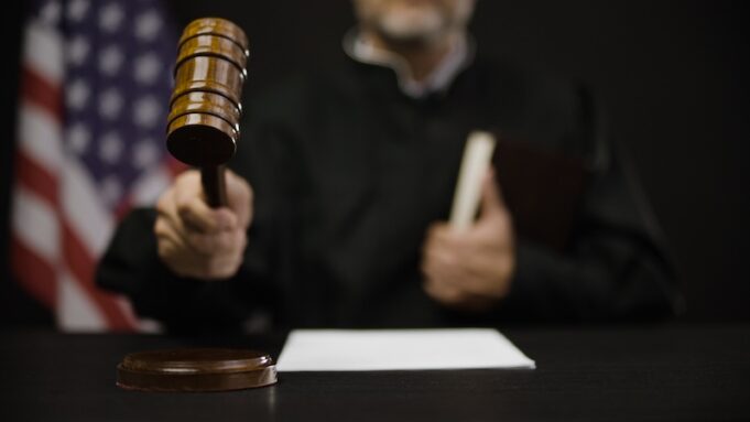 Male judge hitting gavel, calling court members to stand, United States justice system
